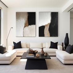 a living room filled with white couches and black tables in front of two paintings