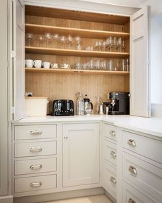 a kitchen with white cabinets and glassware on the shelves