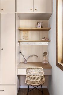 a white desk with a wicker chair in front of it and shelves behind it