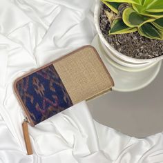 a small purse sitting on top of a white sheet next to a potted plant