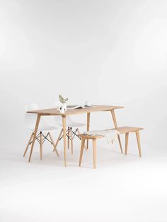 a table with two chairs and a small white vase on it next to a wooden bench