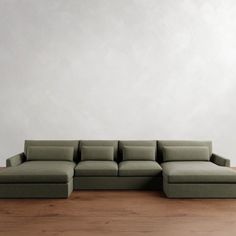 a green couch sitting on top of a hard wood floor next to a white wall