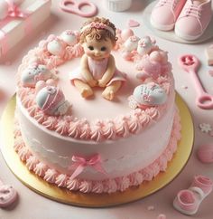 a cake decorated with pink icing and baby items on top of a white table