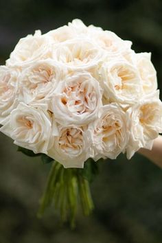 a bouquet of white flowers being held by someone's hand