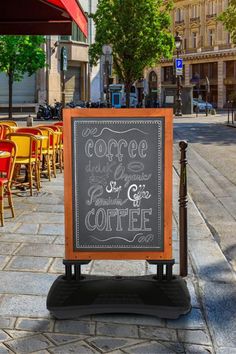 a chalkboard sign sitting on the sidewalk in front of some tables with yellow chairs