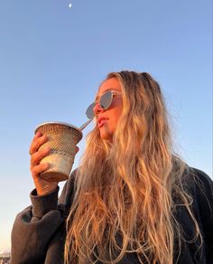 a woman with long hair drinking from a cup