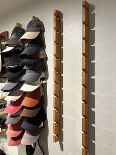 several hats are hanging on the wall next to two wooden racks with hat hangers