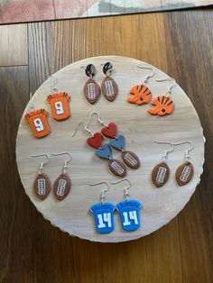 a wooden board topped with different types of earrings on top of a wood table next to a rug