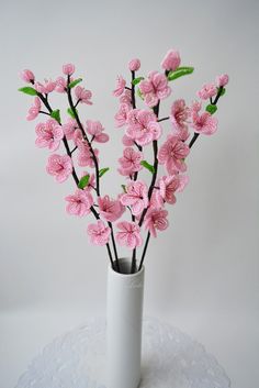 pink flowers are in a white vase on a doily