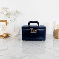 a blue suitcase sitting on top of a marble counter next to candles and flowers in vases