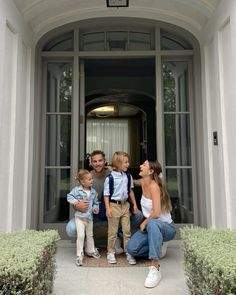 a man, woman and two children are standing in front of a building with an entrance