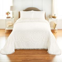 a bed with white bedspread and pillows in a room