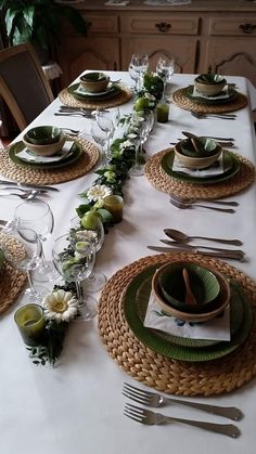 the table is set with plates, silverware and green napkins for dinner guests