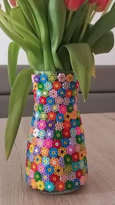 a colorful vase filled with flowers on top of a wooden table