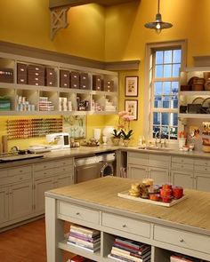 a large kitchen with yellow walls and white cabinets is pictured in this image, there are many books on the shelves