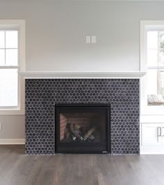 an empty living room with a fireplace and windows