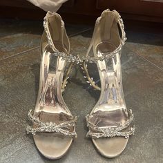 a pair of silver high heeled shoes sitting on top of a floor