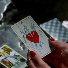 a woman holding up a tarot card in her left hand with an arrow drawn on it