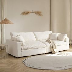 a white couch sitting on top of a wooden floor next to a lamp and rug