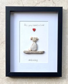 a white and black frame with a teddy bear in it's lap that says, all you need is love and a red heart