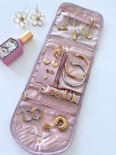 a pink purse with lots of jewelry on it and a bottle of perfume next to it