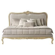 a white bed with lots of pillows on it's headboard and foot board