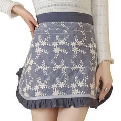 a woman wearing a skirt with white flowers on the bottom and blue trimmings