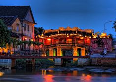 a bridge over a river with buildings on both sides and lights reflecting in the water