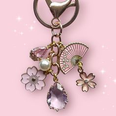 a keychain with charms and flowers on it, sitting on a pink background