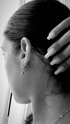 a woman with her hair in a bun is wearing earring and looking out the window