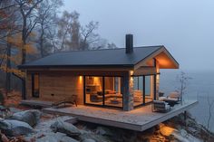 a small cabin on the edge of a cliff by the water at night with its lights on