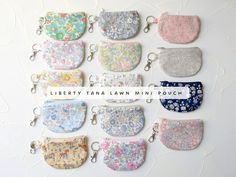 a bunch of small purses hanging on a wall with the words liberty tana law mini pouch