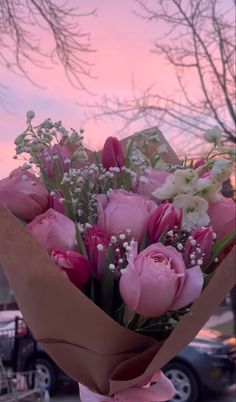 a bouquet of flowers is wrapped in brown paper with pink and white flowers on it