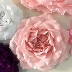 pink, white and purple flowers are arranged on a table top with one flower in the center