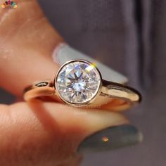 a woman's hand holding a gold ring with a diamond on the top and bottom