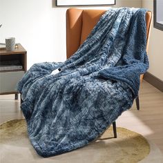 a blue blanket sitting on top of a chair next to a brown chair in a living room