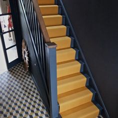 the stairs are painted yellow and black with checkerboard flooring on both sides