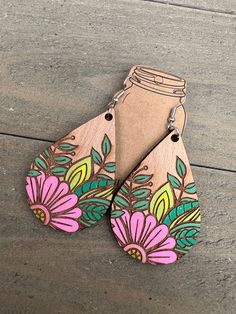 two wooden earrings with flowers painted on them are sitting on the ground next to each other