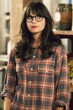 a woman wearing glasses standing in front of a book shelf