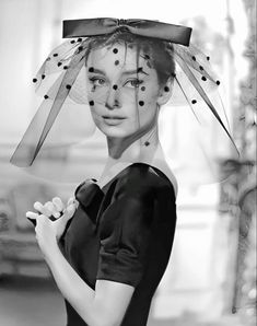 black and white photograph of a woman wearing a veil over her head with polka dots on it