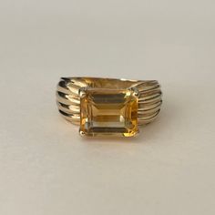 Clyde Duneier 14K Meral Cut Citrine Ring with Ribbed Band, Size 7, 5.1 grams, November Birthstone Size: 7 Weight: 5.1 grams Stones: Citrine Size Stone: ca. 10.2mm x 8mm Color Gemstone: Honey-Orange Number of Gemstones: 1 Cut: Emerald Material: 14 Karat Yellow Gold Band Width: ca. 2.9mm at smallest point Marking: 14K CID Manufacturer: Clyde Duneier Condition: Good preowned, light usage throughout -refer to pictures for condition. Band is slightly bent. All jewelry will be professionally cleaned before shipping and come in a beautiful little gift box. Returns accepted but are subjected to a 7% restock fee. Returns are only accepted for national orders. Classic Oval Yellow Gold Gemstone, Classic Formal Gemstones With Polished Finish, Classic Round Gold Gemstones, Vintage Faceted Yellow Gold Rings, Octagon Shaped Citrine Jewelry In Yellow Gold, Timeless Citrine Rings For Formal Occasions, Formal Yellow Gold Jewelry With Rectangular Stone, Classic 14k Gold Gemstones, Classic 14k Gold Gemstones In Gold Color