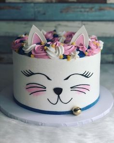 a white cake with pink and blue frosting has a cat's face on it