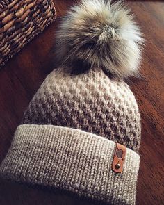 a knitted hat with a fur pom - pom sitting on top of it