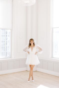 a woman in a white dress is posing for a photo with her hands on her hips