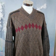 "This 1980s Italian vintage sweater is a warm brown color with a burgundy argyle pattern across the front and back and accented with black fine striping. The wool-mohair blend pullover has a short V neckline with a wide ribbed crossover collar. The sweater has ribbed cuffs and a ribbed waistband. Note that this is a \"short\" size. See especially the sleeve length and sweater length below. Brand label: Nani Bon Size: 46S (US/UK) Material: 40% acrylic, 30% wool, 20% mohair, 10% nylon Chest = 46 i Brown Crew Neck Polo Sweater For Winter, Retro Brown Sweater For Fall, Brown Argyle Pattern Long Sleeve Sweater, Brown Long Sleeve Argyle Sweater, Brown Argyle Long Sleeve Sweater, Vintage Brown Long Sleeve Sweater, Vintage Long Sleeve Brown Sweater, Vintage Argyle Sweater For Fall, Brown Argyle Sweater For Fall