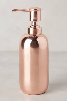 a copper colored soap dispenser on a white background