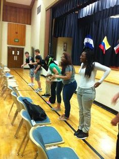 some people are standing in a room with chairs and flags on the wall behind them