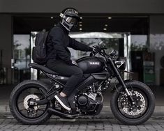 a man sitting on top of a black motorcycle