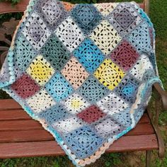 a crocheted blanket sitting on top of a wooden bench