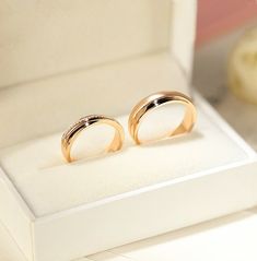 two gold wedding rings sitting in a white box